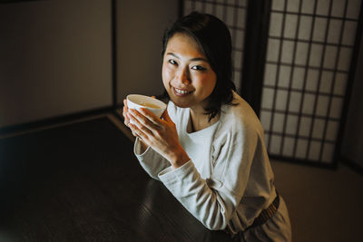 Portrait woman eating food sitting at home