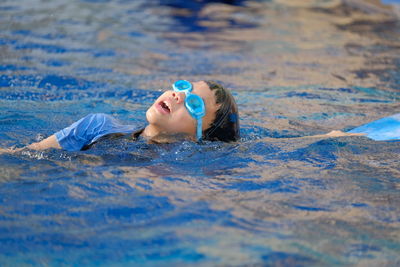 Portrait of boy lying in swimming pool