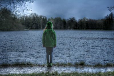 Rear view of woman standing by lake