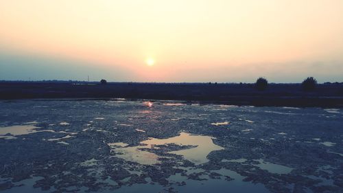 Scenic view of frozen lake against orange sky during sunset