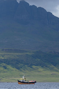 Sailboat on sea against mountain range