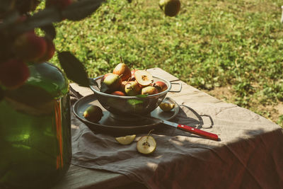 Many ripe pears in a colander on wooden garden table