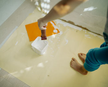 Dipping roller paint into the paint container, high angle view.