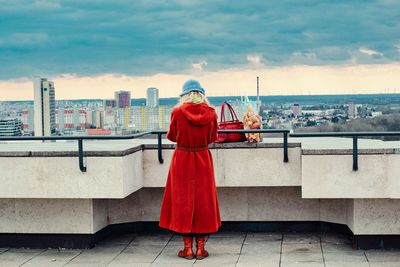 Rear view of woman in red against sky in city