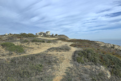 Scenic view of rocky mountain by sea against sky