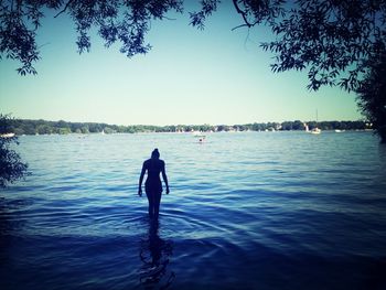 Rear view of silhouette woman standing in lake