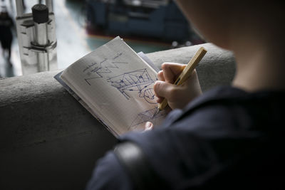 Midsection of girl making sketches on book