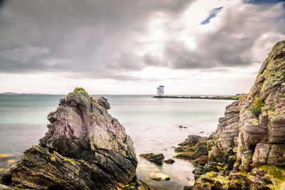 Rock formation on sea shore against sky