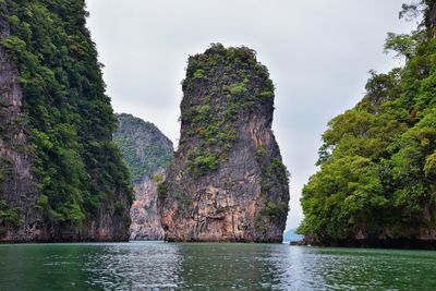 Scenic view of rocks by trees against sky