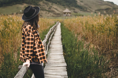 Rear view of woman standing on boardwalk