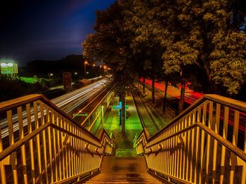 Illuminated footbridge leading towards railroad station platform at night