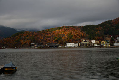 Scenic view of river by buildings against sky