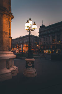 Illuminated street light in city at dusk