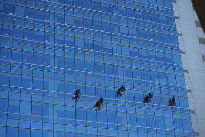 Low angle view of people working on glass building