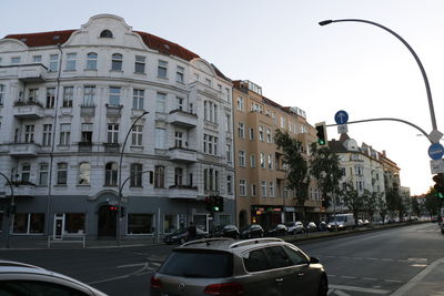 Cars on road by buildings against sky in city