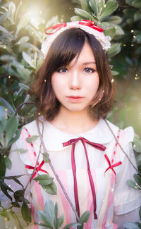 Portrait of a beautiful young woman standing against plants