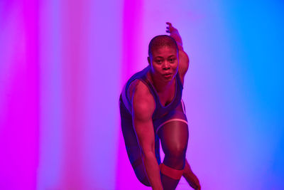 Portrait of woman exercising in front of wall