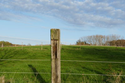 Wooden fence on field against sky