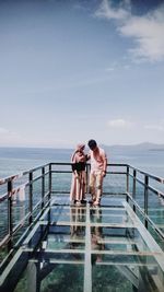 People at observation point by sea against sky