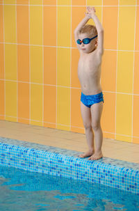 Toddler child learning to dive in indoor swimming pool with teacher. standing on side,