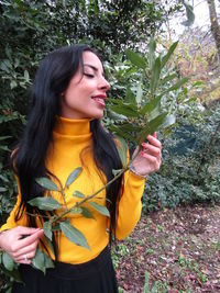 Young woman smiling while standing against plants