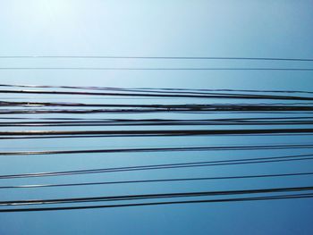 Low angle view of power cables against clear sky