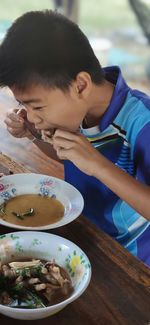 Side view of boy eating food at table