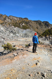 Rear view of man on standing on field against rock mountains