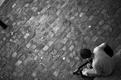 High angle view of girl sitting on sidewalk