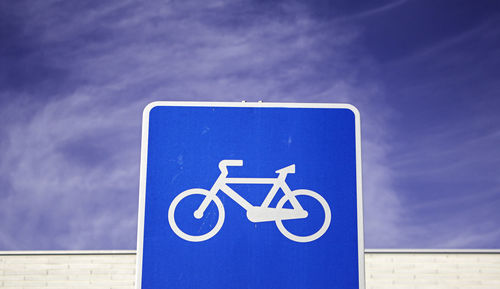 Close-up of bicycle lane sign against blue sky