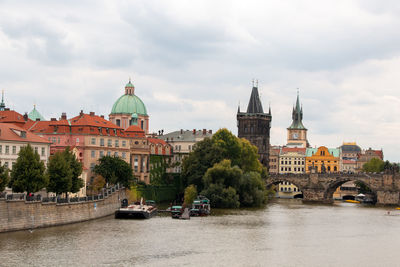 Bridge over river amidst buildings in city against sky