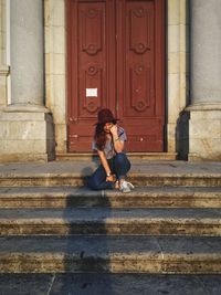 Full length of woman sitting on staircase