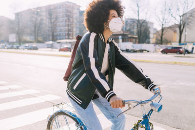 Young woman riding bicycle on road in city