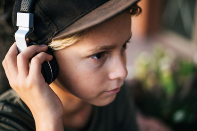 Close-up portrait of boy holding mobile phone outdoors