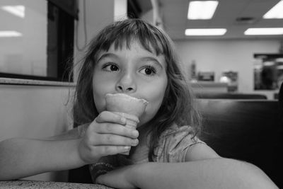 Close-up of thoughtful girl having ice cream cone while sitting in restaurant