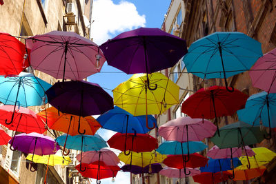 Low angle view of umbrellas hanging amidst buildings