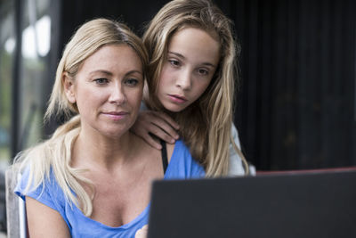 Mother and daughter using laptop at yard