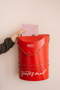 A child puts a letter to santa claus in a red christmas mailbox