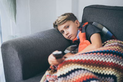 Boy sitting on sofa at home