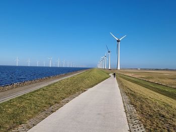 Wind turbines on road against sky