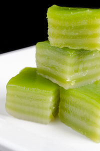 Close-up of green fruit in plate against black background