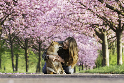 Smiling woman pampering dog on road