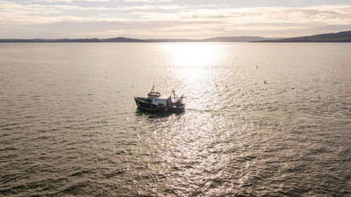 Boat sailing on sea against sky during sunset