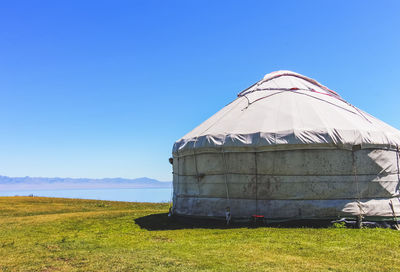 Built structure on field against clear blue sky