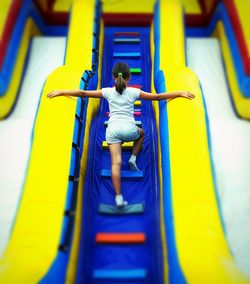 Rear view of girl playing on bouncy castle