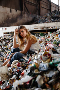 Portrait of young woman sitting on garbage
