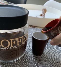 Close-up of hand holding coffee cup on table