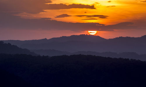 Scenic view of silhouette mountains against orange sky
