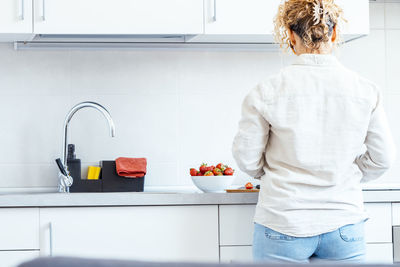 Rear view of woman standing in bathroom