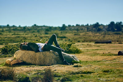 Portrait of young tattoed man lying on a rock smoking